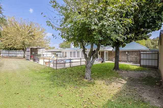 a view of backyard with large trees and wooden fence