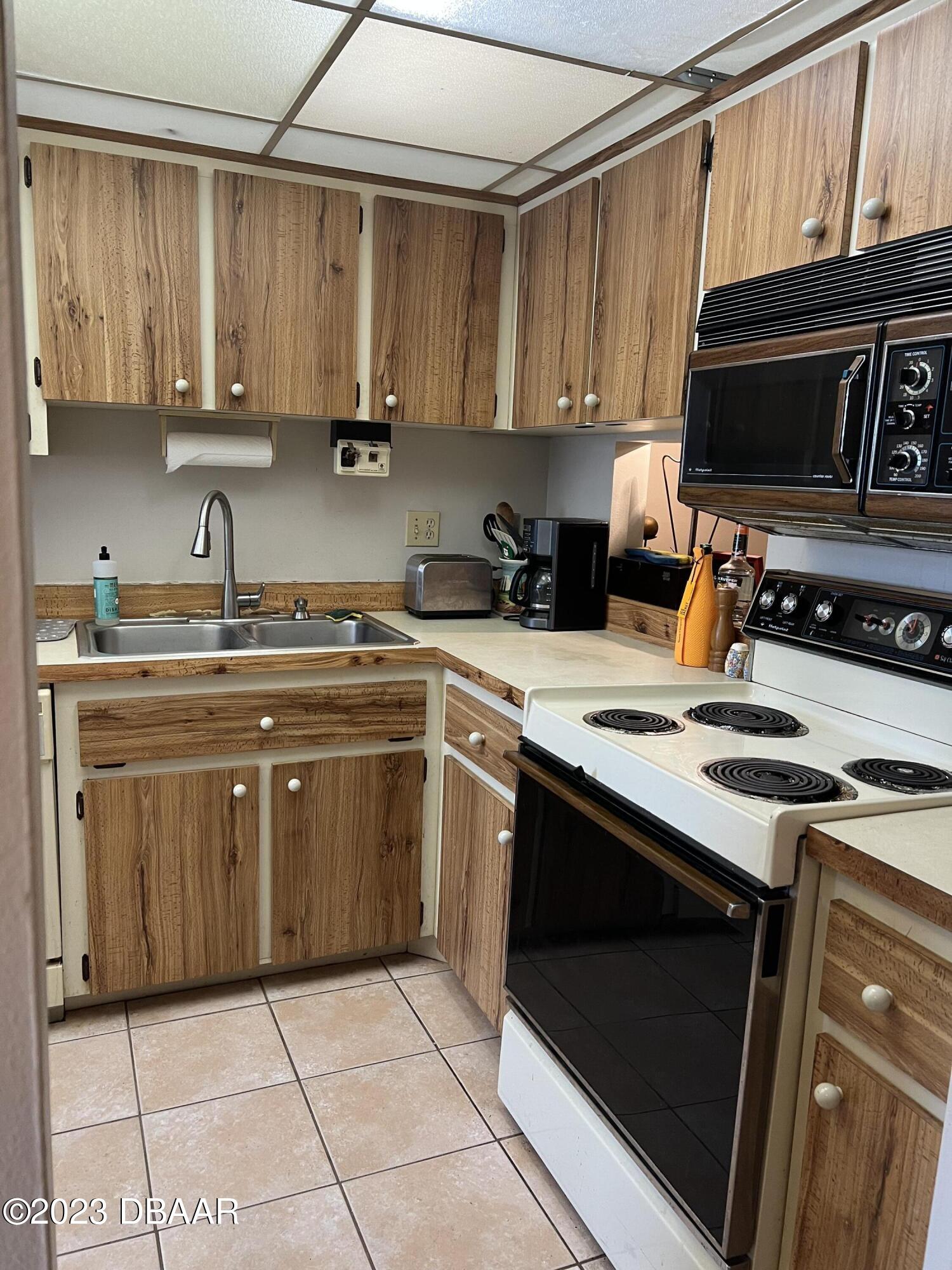 640 North Nova Road, Unit 204 Ormond Beach, FL 32174 - Photo 3 of 17 a kitchen with a stove a microwave and wooden cabinets