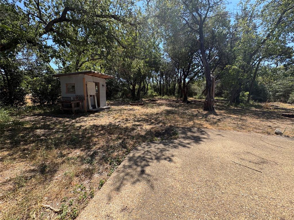 5454 Ranchero Lane Dallas, TX 75236 - Photo 23 of 24 Wooded lot featuring mature trees and a gravel pathway