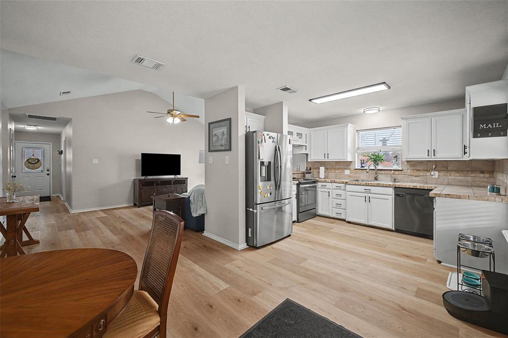 323 Sage Trail Springtown, TX 76082 - Photo 12 of 32 a kitchen with a refrigerator a microwave oven a sink dishwasher and white cabinets with wooden floor