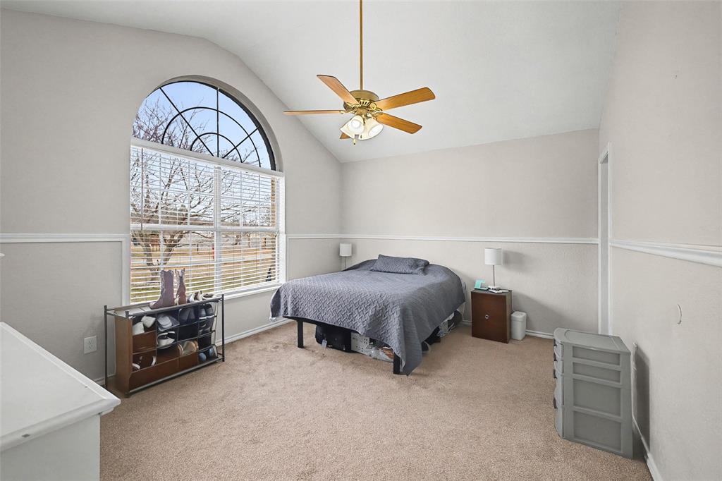 323 Sage Trail Springtown, TX 76082 - Photo 20 of 32 a spacious bedroom with a bed a chandelier and a window