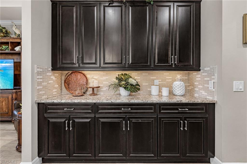 1434 Redona Way Naples, FL 34113 - Photo 21 of 47 a sink with granite countertop wooden cabinets