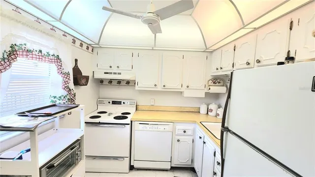 a kitchen with stainless steel appliances a white refrigerator stove and white cabinets