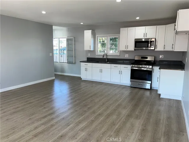 a large kitchen with stainless steel appliances granite countertop a stove a sink and a microwave