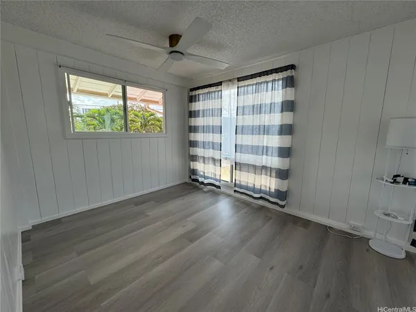 a view of an empty room with a window and wooden floor
