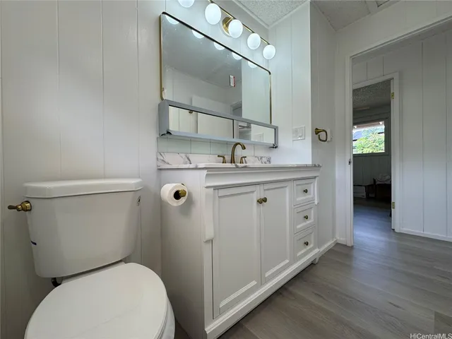 a bathroom with a granite countertop toilet sink and mirror