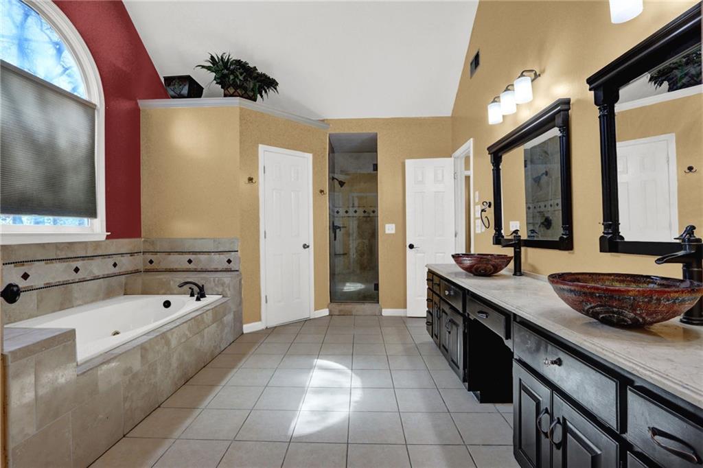 5010 Oak Tree Lane Stone Mountain, GA 30087 - Photo 26 of 35 a spacious bathroom with a granite countertop sink a mirror and a bathtub