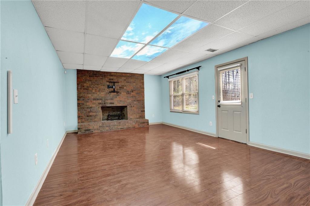 5010 Oak Tree Lane Stone Mountain, GA 30087 - Photo 30 of 35 an empty room with windows fireplace and wooden floor