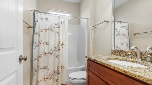 a bathroom with a granite countertop sink toilet and shower