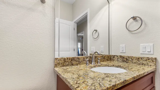 a bathroom with a granite countertop sink and a mirror