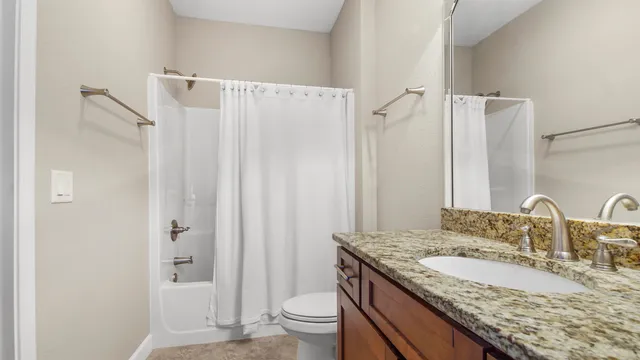 a bathroom with a granite countertop sink a toilet and shower