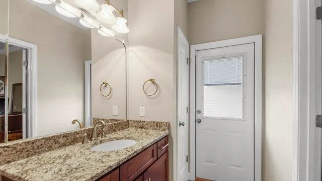 a bathroom with a granite countertop sink a mirror and a shower