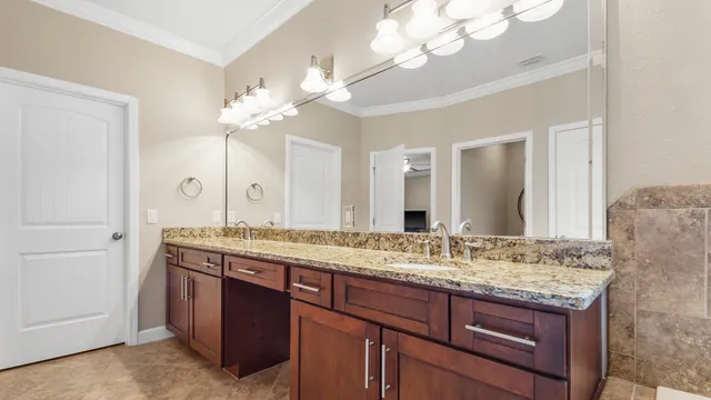 a bathroom with a granite countertop double vanity sink and a mirror