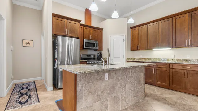 a kitchen with stainless steel appliances granite countertop a stove a sink and a refrigerator with wooden cabinets