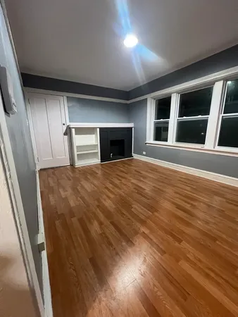 a view of empty room with wooden floor and fireplace