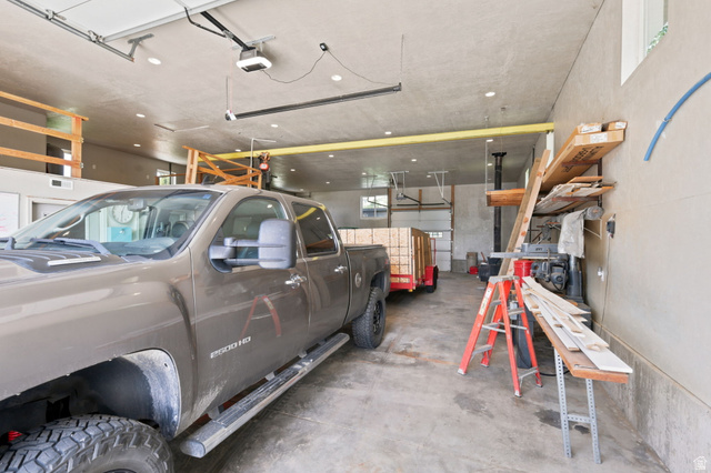 580 North 300 East Logan, UT 84321 - Photo 61 of 74 Spacious garage featuring a concrete floor, multiple automatic garage doors, abundant overhead lighting, high ceilings, and an exposed overhead beam