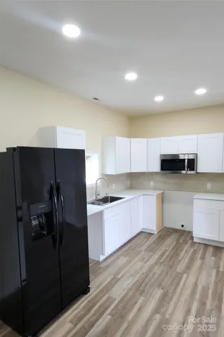 a kitchen with stainless steel appliances kitchen island granite countertop a refrigerator and a sink