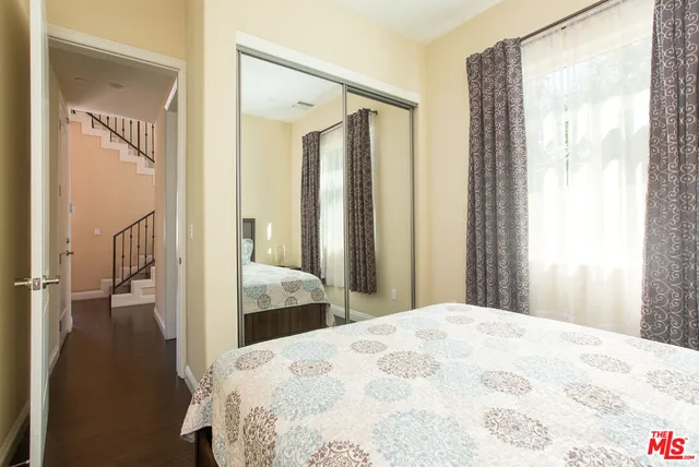 a bedroom with a bed and a large mirror next to a window