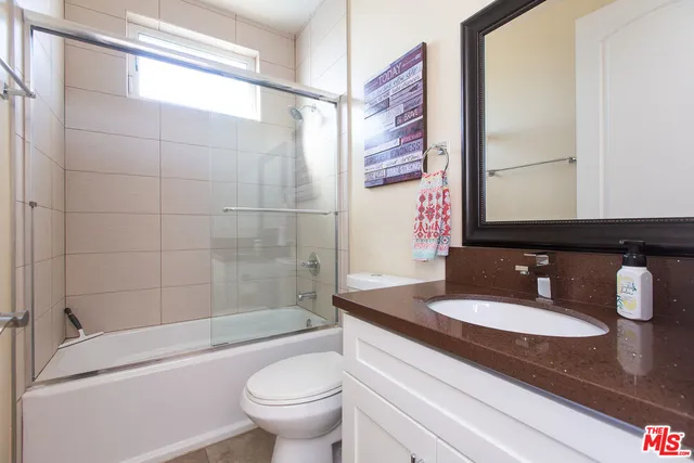 a bathroom with a granite countertop sink toilet and shower
