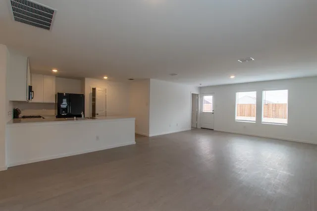 a view of empty room with wooden floor and windows
