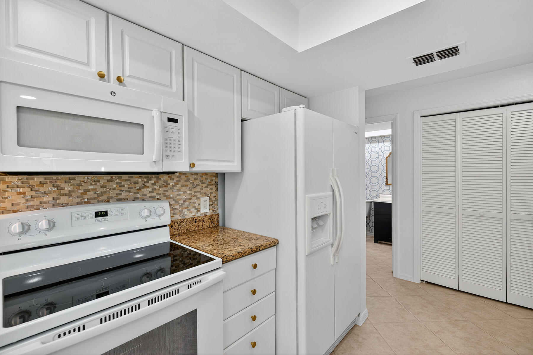 3136 Kings Lake Boulevard, Unit 7546 Naples, FL 34112 - Photo 8 of 32 a kitchen with stainless steel appliances white cabinets and a refrigerator
