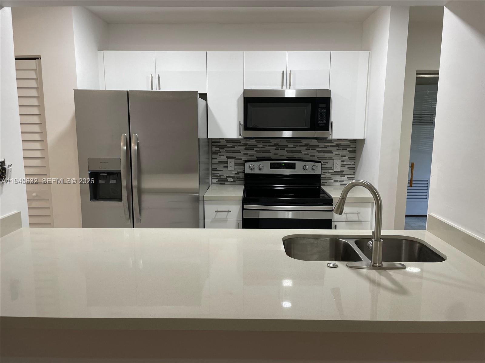 15325 Southwest 106th Terrace, Unit 618 Miami, FL 33196 - Photo 8 of 27 a kitchen with stainless steel appliances a stove a microwave a sink a refrigerator and white cabinets