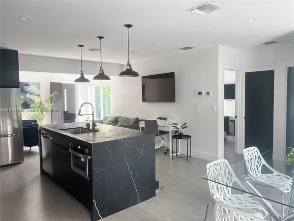 a kitchen with stainless steel appliances granite countertop a stove top oven a sink dishwasher a dining table and chairs with wooden floor