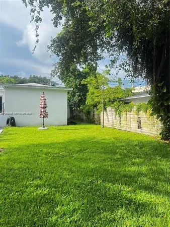 a view of a house with a yard and a large tree