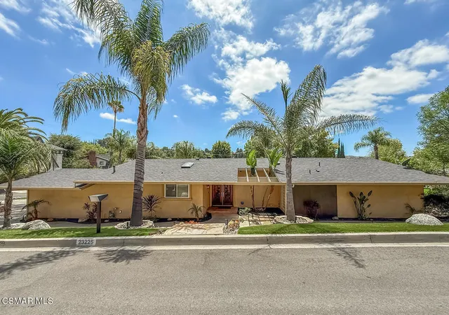 a view of a house with a yard and palm trees