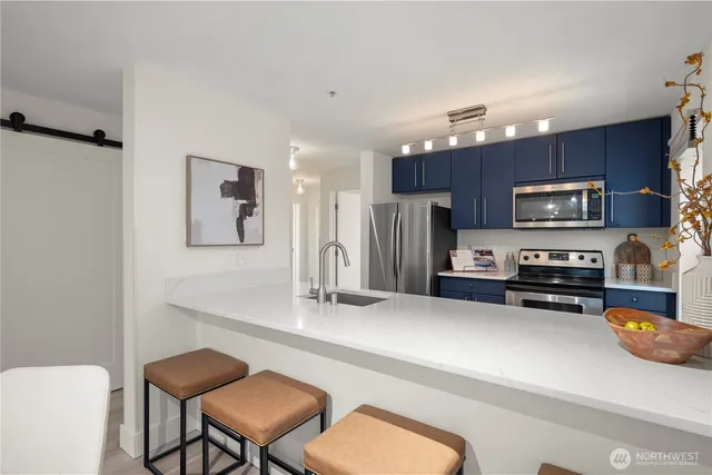 a kitchen with stainless steel appliances a sink a stove a refrigerator cabinets and dining table