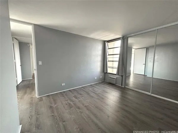an empty room with wooden floor and windows