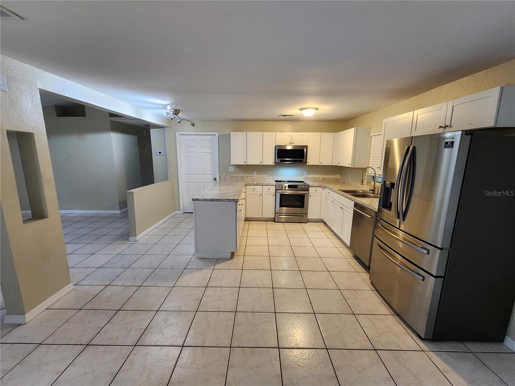 249 Flamingo Road Oak Hill, FL 32759 - Photo 7 of 11 a kitchen with stainless steel appliances a refrigerator sink and cabinets