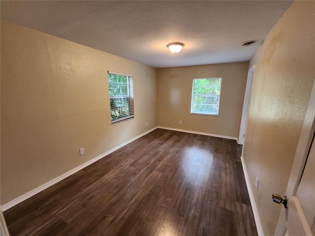 249 Flamingo Road Oak Hill, FL 32759 - Photo 9 of 11 an empty room with wooden floor and windows