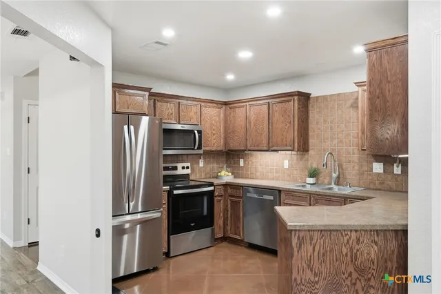 a kitchen with stainless steel appliances a refrigerator sink and microwave