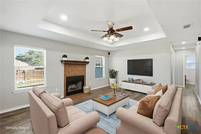 a view of an empty room with wooden floor fireplace and a window