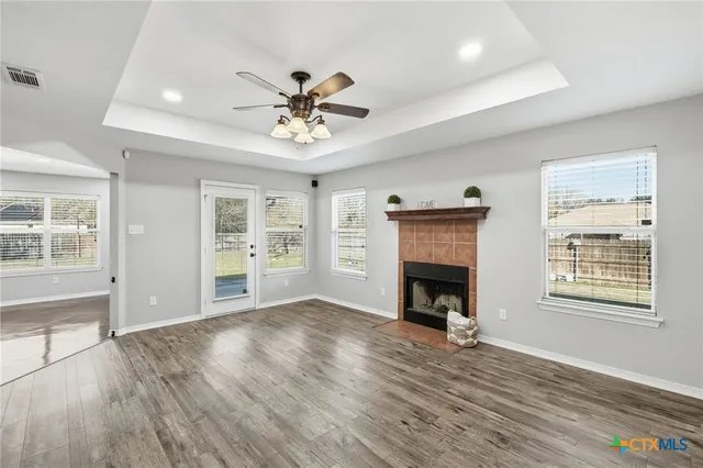 a view of an empty room with window and wooden floor
