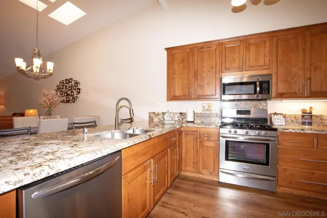 a kitchen with stainless steel appliances granite countertop a stove a sink and a microwave