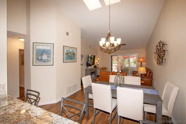 a dining room with wooden floor a chandelier a wooden table and chairs