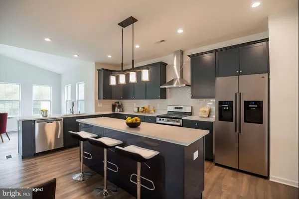 a kitchen with stainless steel appliances granite countertop a sink a stove a refrigerator and island