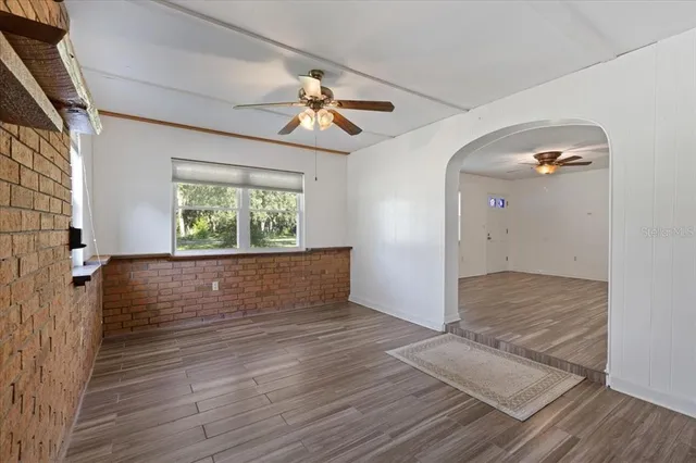 an empty room with a chandelier fan and windows