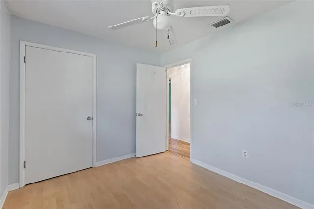 an empty room with closet and a ceiling fan