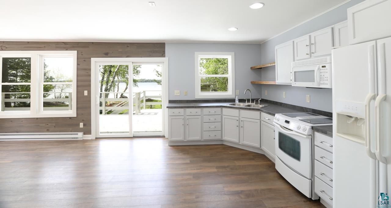 3739 Sundling Road Tower, MN 55790 - Photo 3 of 15 Kitchen featuring dark wood-type flooring, baseboard heating, white cabinetry, and white appliances