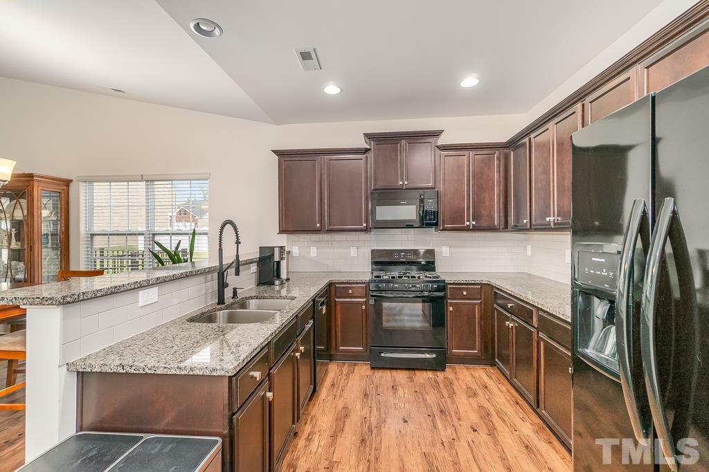 1505 Stark Spring Street Raleigh, NC 27610 - Photo 13 of 22 a kitchen with stainless steel appliances granite countertop sink stove refrigerator and cabinets