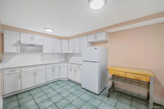 a kitchen with a refrigerator and white cabinets