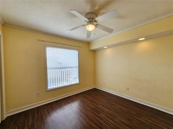 an empty room with wooden floor and fan