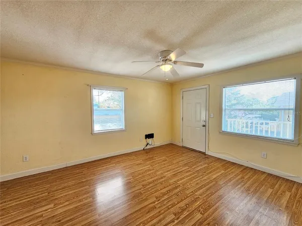 a view of a room with wooden floor and a ceiling fan