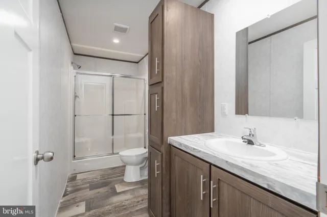 a bathroom with a granite countertop sink a toilet and shower