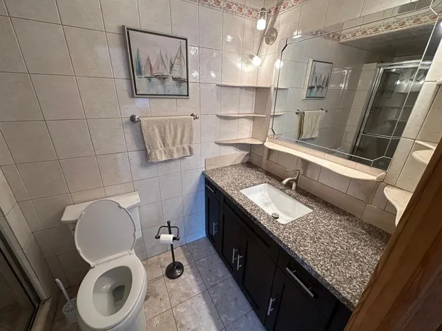 a bathroom with a granite countertop toilet and a sink