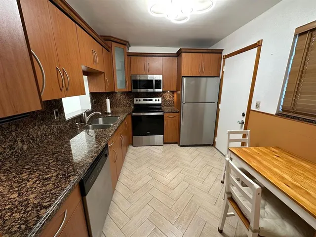 a kitchen with granite countertop a refrigerator stove and sink