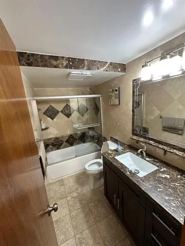 a bathroom with a granite countertop sink a mirror and a bathtub